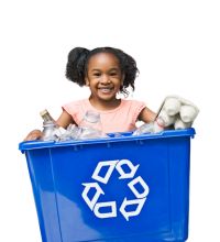 photo of child smiling with recycling bin