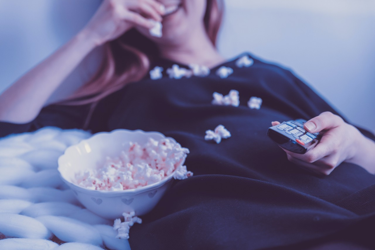 Woman-eating-popcorn-with-TV-remote-in-han_20211004-235451_1